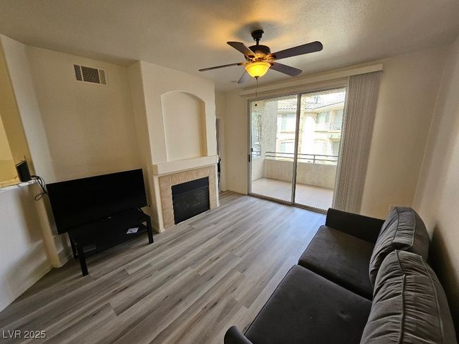 Living area with wood finished floors, ceiling fan, a tile fireplace, baseboards, and visible vents | Image 31