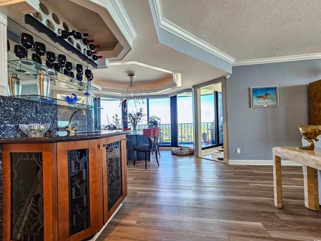 Bar with crown molding, wood finished floors, baseboards, indoor bar, and a tray ceiling | Image 18