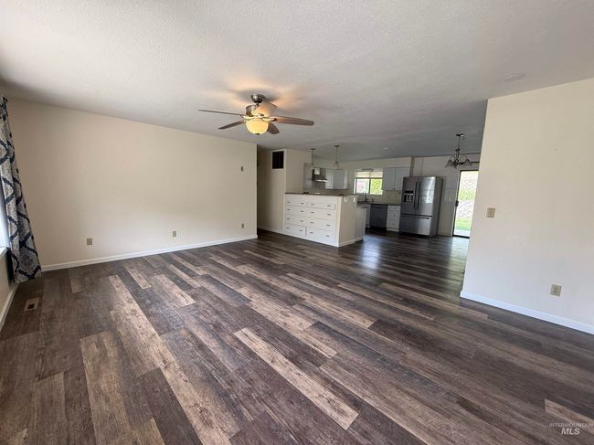 Unfurnished living room with ceiling fan, dark wood-style floors, a textured ceiling, and a chandelier | Image 19