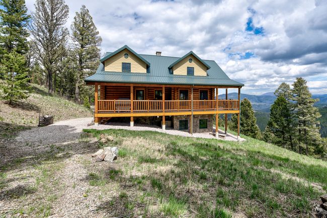 Rear view of house with log exterior, a deck with mountain view, a metal roof, and stone siding | Image 57