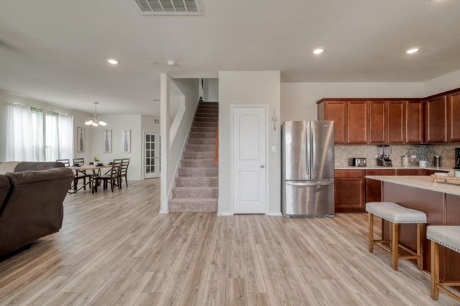 Kitchen featuring light countertops, backsplash, freestanding refrigerator, open floor plan, and visible vents | Image 12