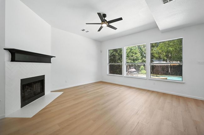 Unfurnished living room featuring light wood-style flooring, a fireplace with flush hearth, and ceiling fan | Image 10