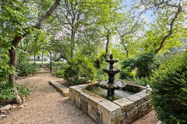 A lovely multi-tiered fountain anchors the front garden, surrounded by native plants and shaded by a canopy of mature trees. Looking towards the street. | Image 4