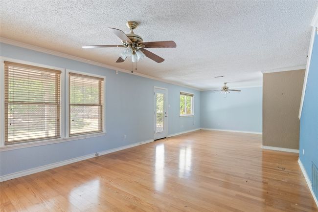 Spare room featuring a ceiling fan, crown molding, a textured ceiling, light wood-style flooring, and baseboards | Image 11