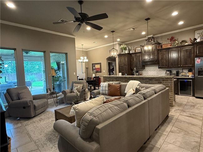 Living area featuring recessed lighting, beverage cooler, crown molding, ceiling fan, and a chandelier | Image 4