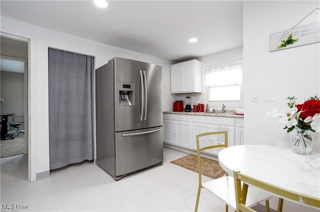 Kitchen with a sink, stainless steel fridge, white cabinetry, light stone countertops, and recessed lighting | Image 7
