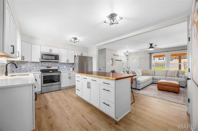 Kitchen featuring appliances with stainless steel finishes, butcher block counters, light wood finished floors, backsplash, and open floor plan | Image 8