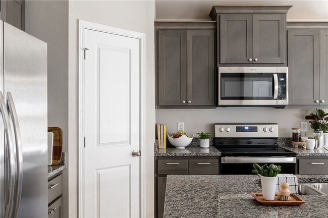 Kitchen with dark stone countertops and stainless steel appliances | Image 7