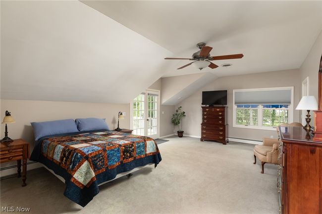 Carpeted bedroom with multiple windows, baseboard heating, ceiling fan, and vaulted ceiling | Image 38
