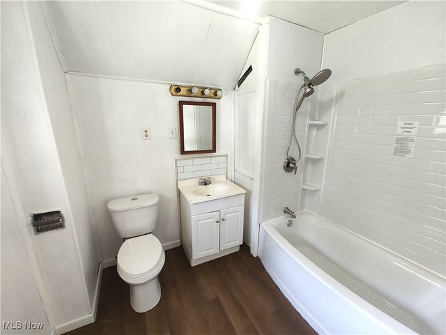 Bathroom with vanity, wood finished floors, toilet, shower / bathtub combination, and lofted ceiling | Image 33