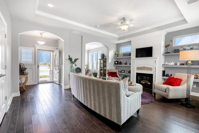 Living room with dark hardwood / wood-style floors, ceiling fan, and a raised ceiling | Image 2