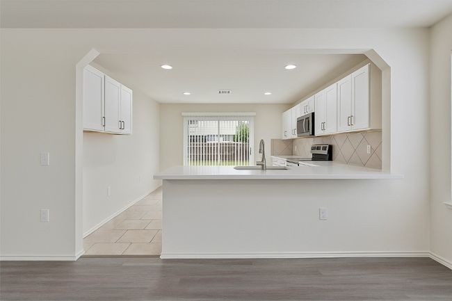Kitchen featuring stainless steel appliances, a peninsula, tasteful backsplash, light countertops, and recessed lighting | Image 5