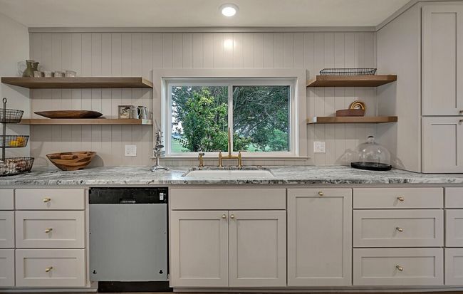 Kitchen with stainless steel dishwasher, open shelves, granite countertops, and backsplash | Image 15