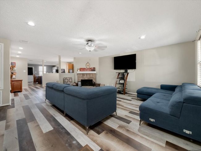 Living room with a textured ceiling, a brick fireplace, hardwood / wood-style floors, and ceiling fan | Image 4