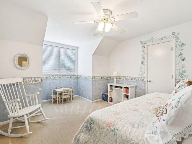 Carpeted bedroom featuring wallpapered walls, a wainscoted wall, baseboards, ceiling fan, and lofted ceiling | Image 22