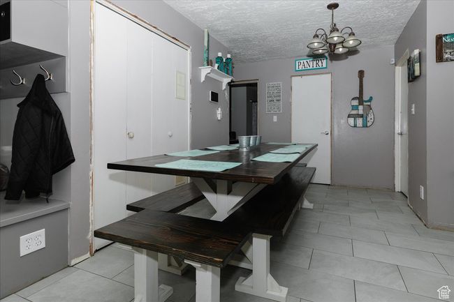 Dining space with a textured ceiling, light tile patterned flooring, and a notable chandelier | Image 7