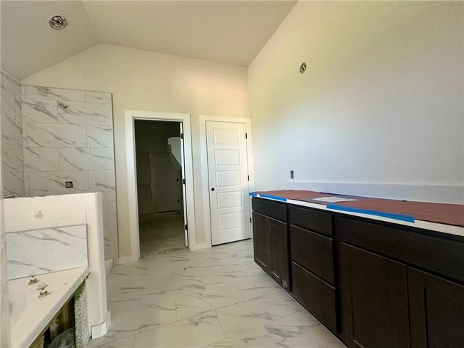 Bathroom featuring marble finish floors, vaulted ceiling, and a shower | Image 10