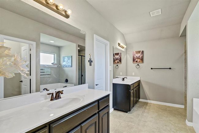 Bathroom featuring tile floors, dual sinks, vanity with extensive cabinet space, and a bathtub | Image 20