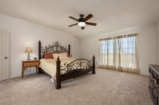 Bedroom with light carpet, a textured ceiling, vaulted ceiling, and ceiling fan | Image 24