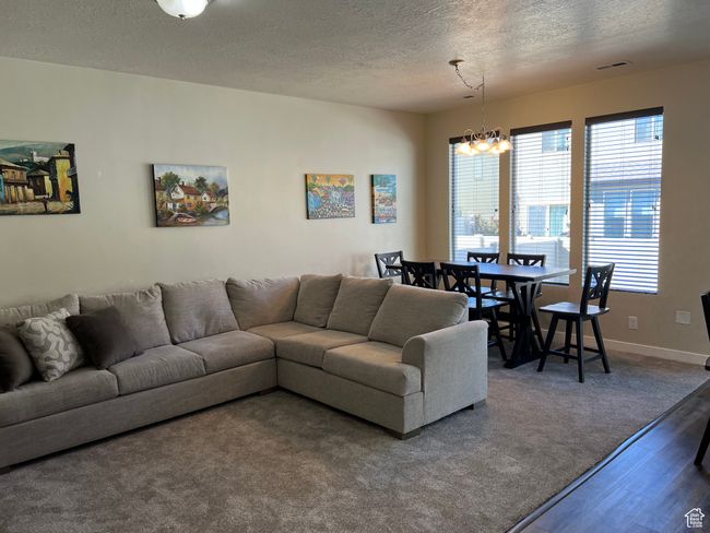 Living area featuring wood finished floors, an inviting chandelier, baseboards, visible vents, and a textured ceiling | Image 10