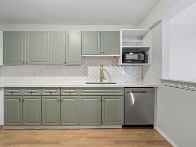 Kitchen featuring light countertops, green cabinetry, a sink, and stainless steel dishwasher | Image 5