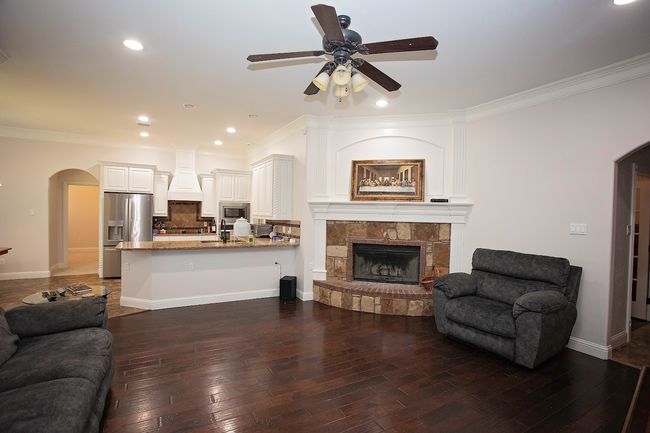 Different angle of living room with hardwood / wood-style flooring, crown molding, a fireplace, a ceiling fan, and recessed lighting | Image 4