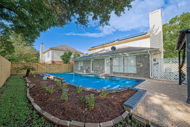Backyard oasis features a saltwater pool and hot tub, all surrounded by a brand-new perimeter fence. Enjoy outdoor living under the pergola, with plenty of space to relax or entertain. Robotic pool cleaners are included for easy maintenance. Spacious yard extends to the side, perfect for play or gardening. | Image 38