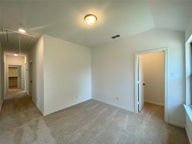 Unfurnished bedroom with attic access, carpet floors, vaulted ceiling, a walk in closet, and a closet | Image 32