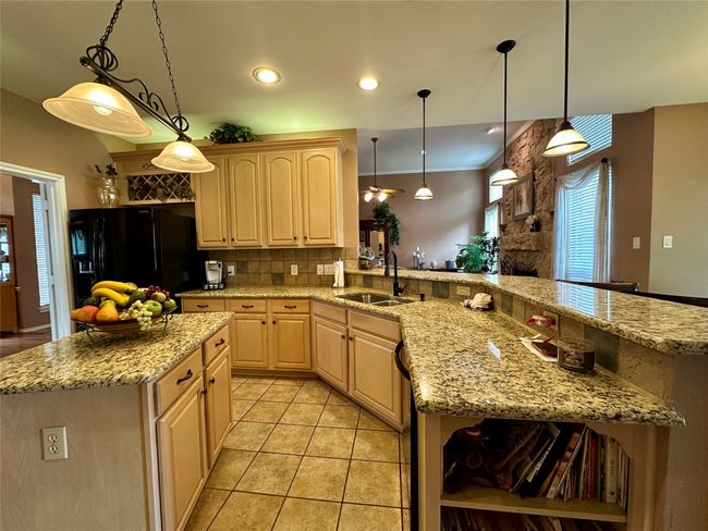 Kitchen featuring a sink, tasteful backsplash, light brown cabinetry, black fridge, and light tile patterned floors | Image 21