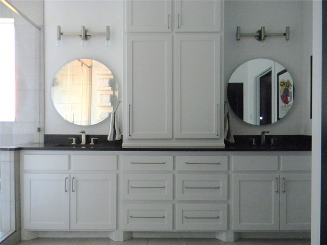 Primary bathroom featuring double vanity and sinks, led lighted mirrors, Kohler faucets and fixtures, decorative lighting and plenty of storage | Image 11