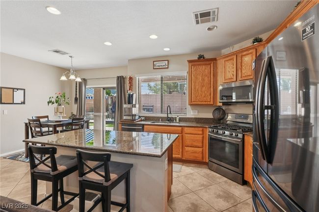Kitchen with appliances with stainless steel finishes, a sink, light tile patterned floors, a kitchen island, and a breakfast bar area | Image 24
