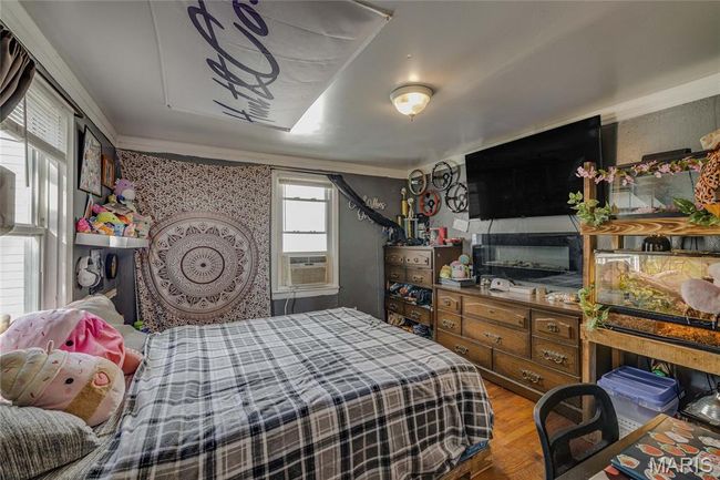 Bedroom featuring wood finished floors, ornamental molding, and cooling unit | Image 9