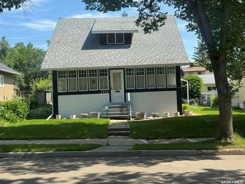 Gable roof with dormer window, white siding, black trim accents, front steps, and a grass lawn | Card Image