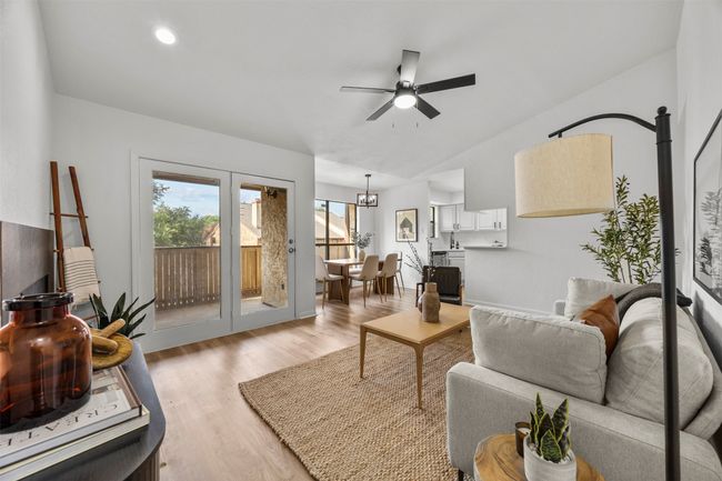 Living room featuring a ceiling fan, light wood-type flooring, vaulted ceiling, and a chandelier | Image 13