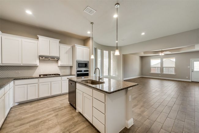 Kitchen with sink, a center island with sink, dark stone counters, pendant lighting, and stainless steel appliances | Image 7
