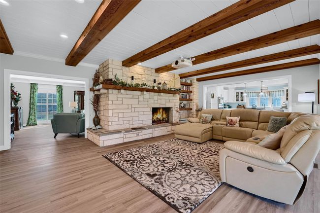 Living room featuring a fireplace, light wood-style floors, and wood ceiling with exposed beams | Image 13