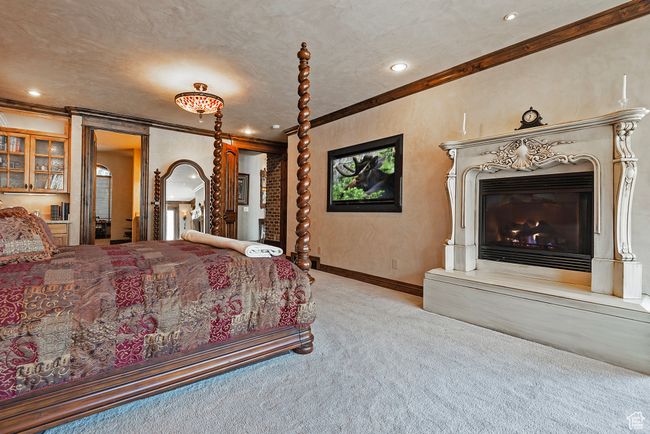 Carpeted bedroom featuring ornamental molding, baseboards, recessed lighting, and a glass covered fireplace | Image 33