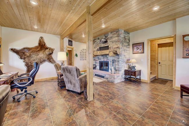 Living area with wooden ceiling, recessed lighting, and a stone fireplace | Image 45