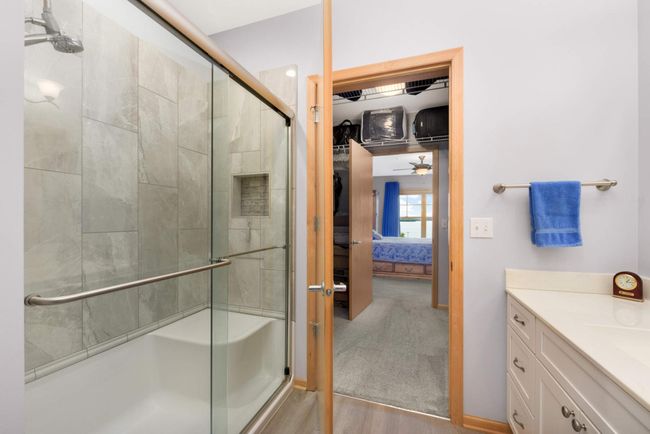 The well-lit walk-in tile shower features a high-quality glass door and a corner seat. | Image 16