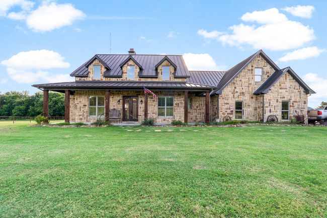 View of front of house with a standing seam roof, covered porch, stone siding, and a metal roof | Image 7