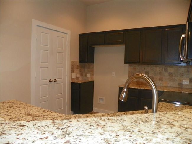 Kitchen featuring stainless steel microwave, decorative backsplash, and light stone countertops | Image 6