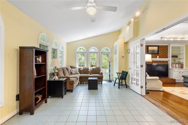 Living room featuring lofted ceiling, a ceiling fan, light tile patterned floors, and a brick fireplace | Image 19