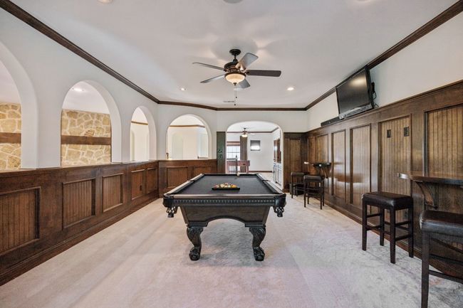 Recreation room with ceiling fan, crown molding, a decorative wall, pool table, and light colored carpet | Image 18