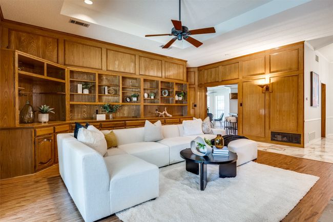 Living area with light wood-style flooring, ceiling fan, a raised ceiling, built in features, and crown molding | Image 5