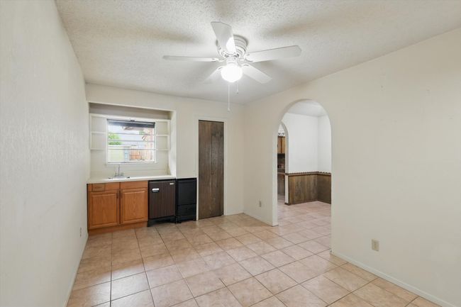 Kitchen featuring arched walkways, a ceiling fan, a textured ceiling, a sink, and light countertops | Image 16