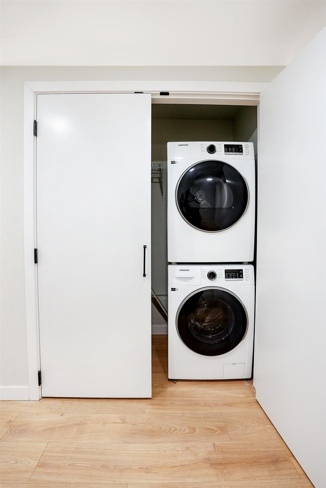Laundry area with light wood-type flooring, stacked washer / drying machine, and laundry area | Image 14