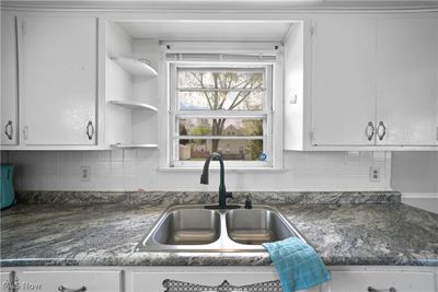 Kitchen with sink, backsplash, white cabinetry, and dark stone counters | Image 2