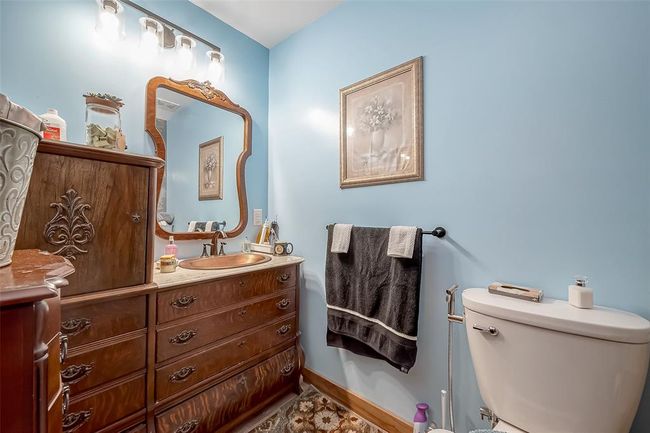 Powder blue walls complement the richness of the wooden vanity, creating a serene retreat within the en suite bath. The framed mirror reflects both style and space. | Image 24
