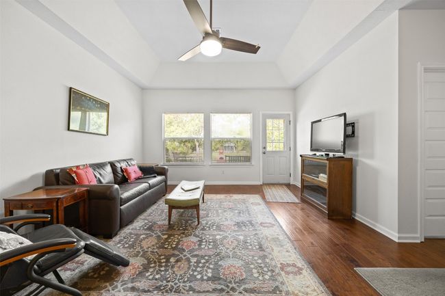 Living room featuring ceiling fan, wood finished floors, and a tray ceiling | Image 5