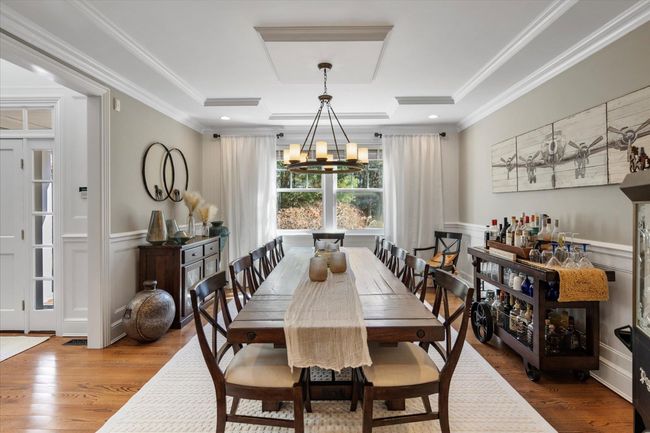 Dining area with an inviting chandelier, wood finished floors, crown molding, and wainscoting | Image 7
